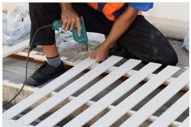 White vinyl fence being repaired by an employee of Eugene Fence Company